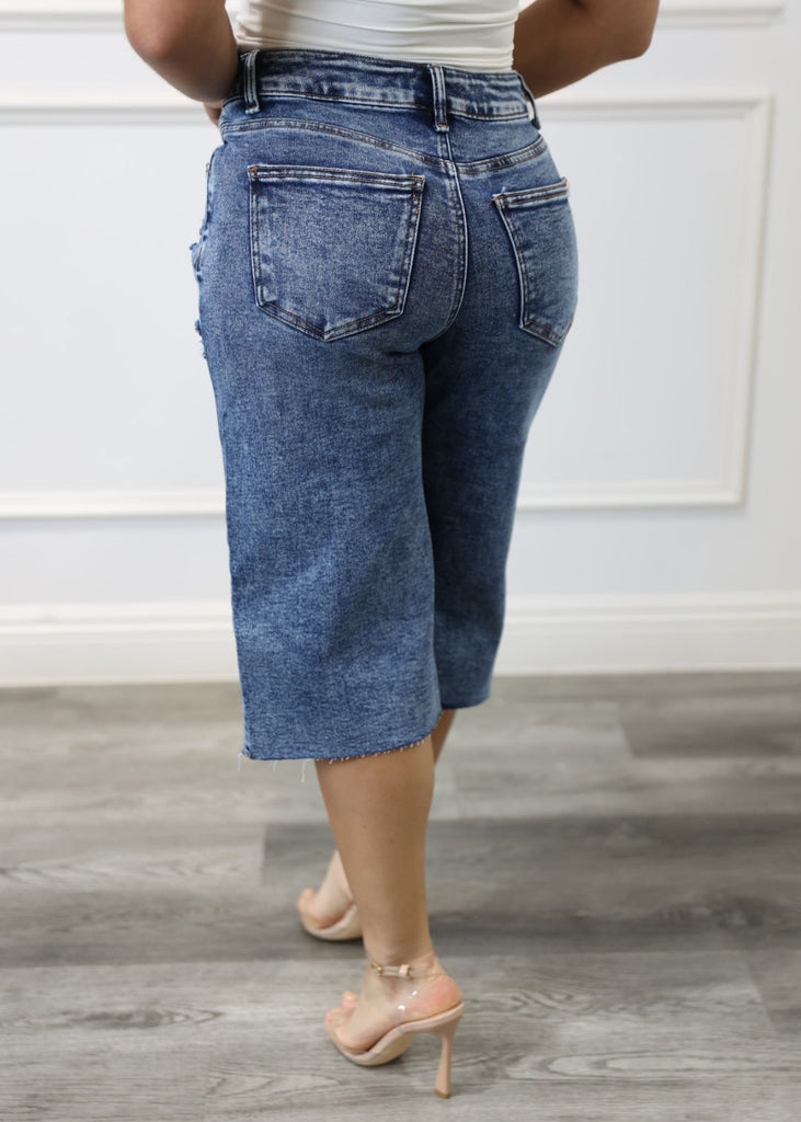 Person wearing blue jeans standing against a neutral background