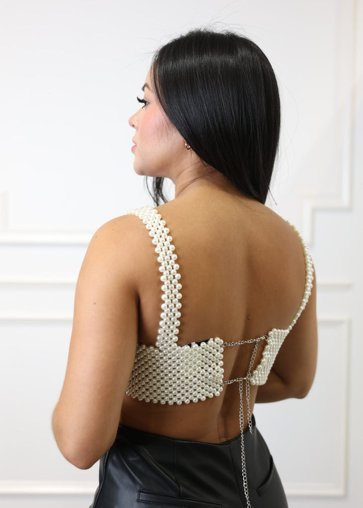 Woman wearing a pearl-encrusted garment against a white background