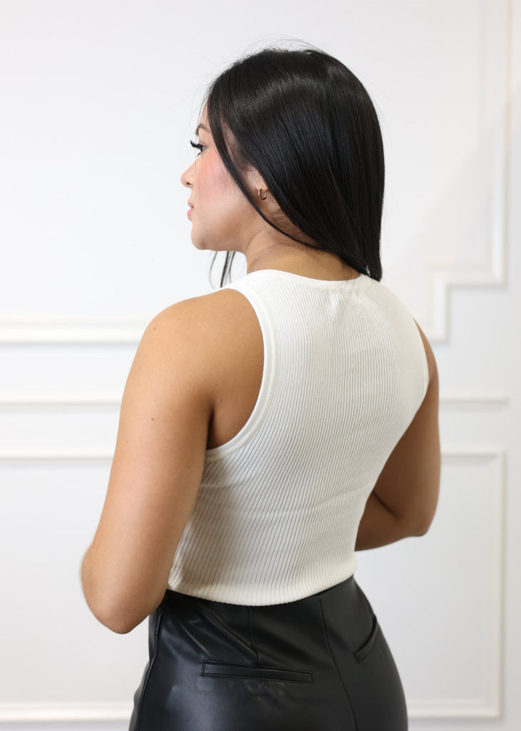 Person wearing a white sleeveless top against a white background